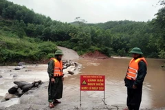 Lực lượng Đồn Biên phòng Ra Mai, huyện Minh Hóa, chốt chặn không cho người dân qua các ngầm tràn khi nước lũ dâng cao. (Ảnh: TTXVN phát)