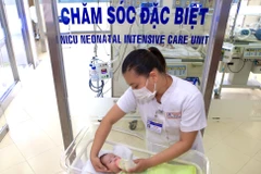 Nữ điều dưỡng Bệnh viện Trung ương Huế tận tình chăm sóc con của một sản phụ mắc COVID-19. (Ảnh: TTXVN phát)