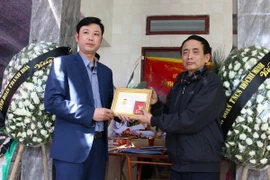 Bí thư Tỉnh đoàn Thanh Hóa Lê Văn Trung truy tặng Huy hiệu “Tuổi trẻ dũng cảm” cho thân nhân em Hải. (Ảnh: Trịnh Duy Hưng/TTXVN)