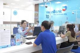 Cán bộ VietinBank hướng dẫn khách hàng xác thực sinh trắc học. (Ảnh: Vietnam+)