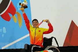 Vận động viên Võ Thanh Tùng tự hào giơ cao tấm huy chương vàng thứ 3 tại Asian Para Games 2018. (Ảnh: Hải Ngọc/TTXVN)