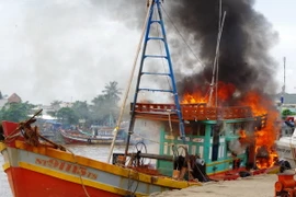 Lực lượng Biên phòng Sóc Trăng cùng nhân dân tham gia chữa cháy tàu cá của ngư dân. (Ảnh: Trung Hiếu/TTXVN)